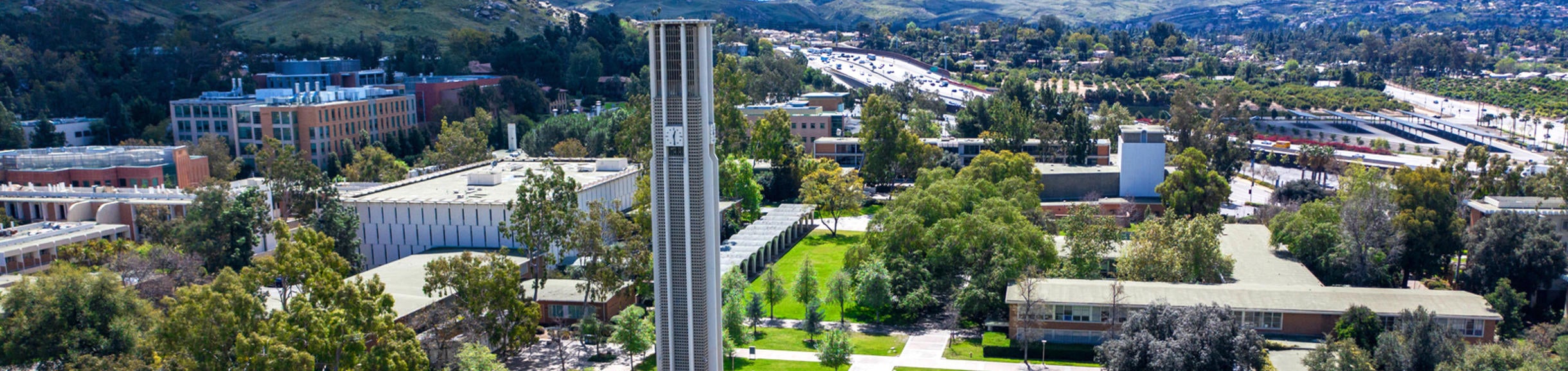The UC Riverside campus with the Bell Tower in the forefront and the southern part of campus and the 215/60 freeway in the background